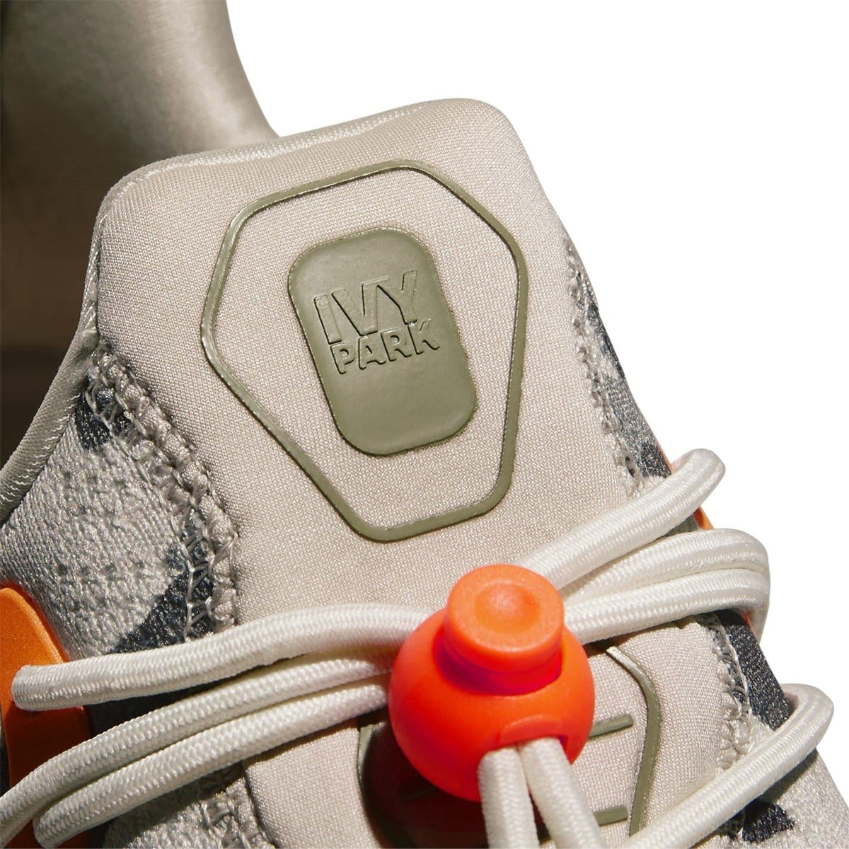 Heel and lace tab detail on camo trainers with orange lace cover