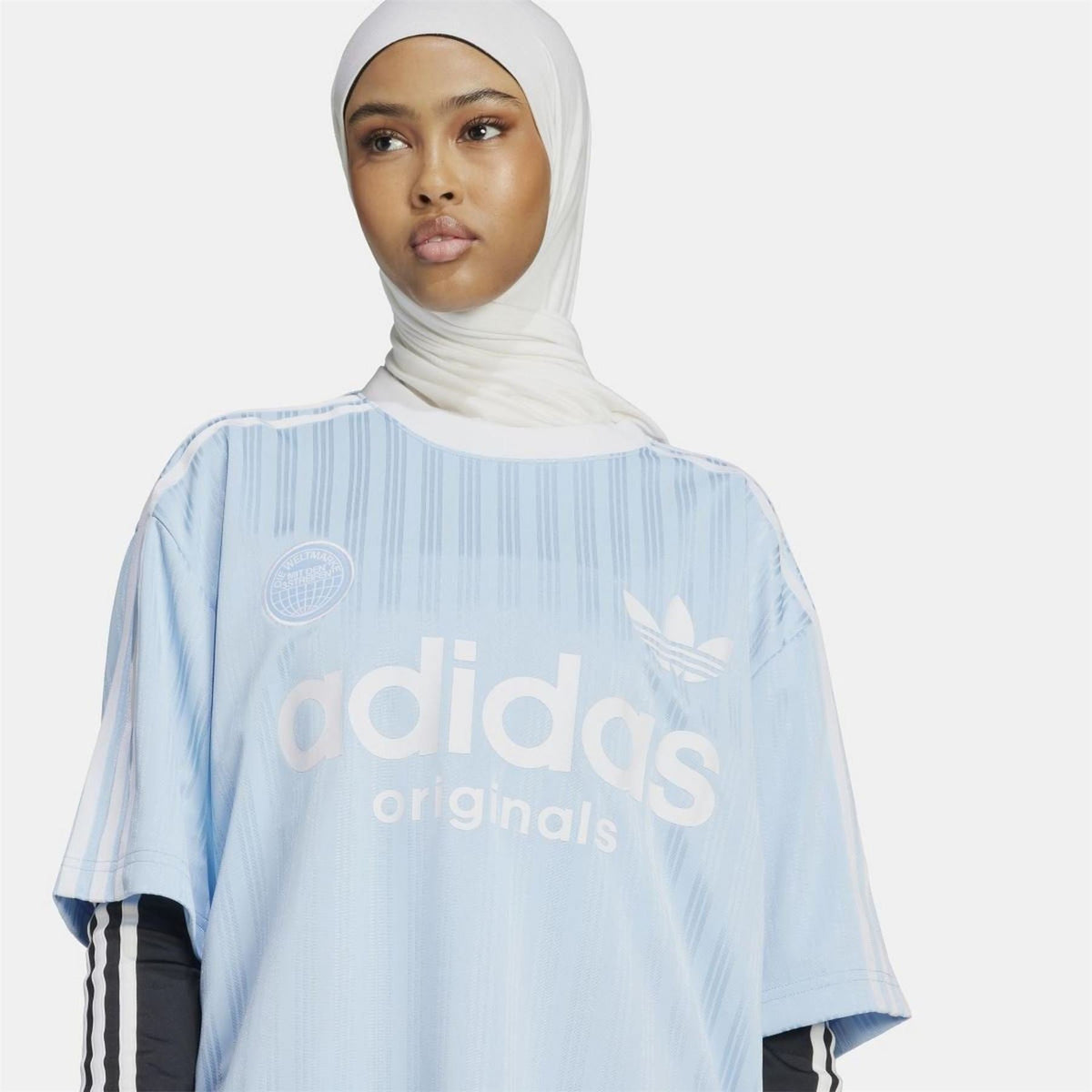 Light blue adidas Originals T-shirt close-up on chest logo, trefoil emblem, striped pattern