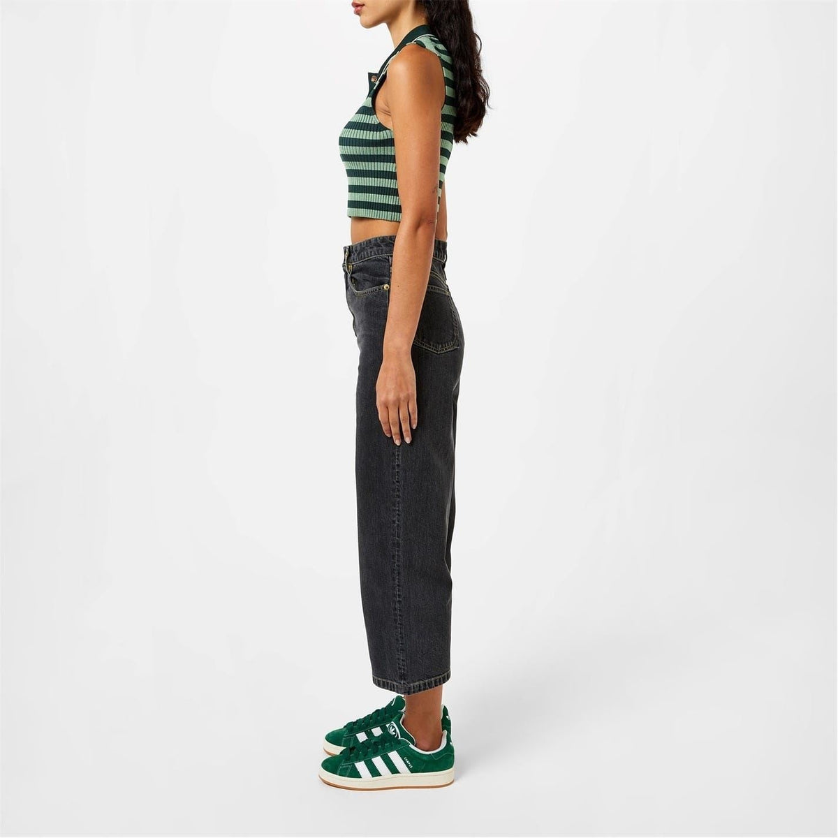 Green adidas sneakers with white stripes and gum sole, worn with dark jeans