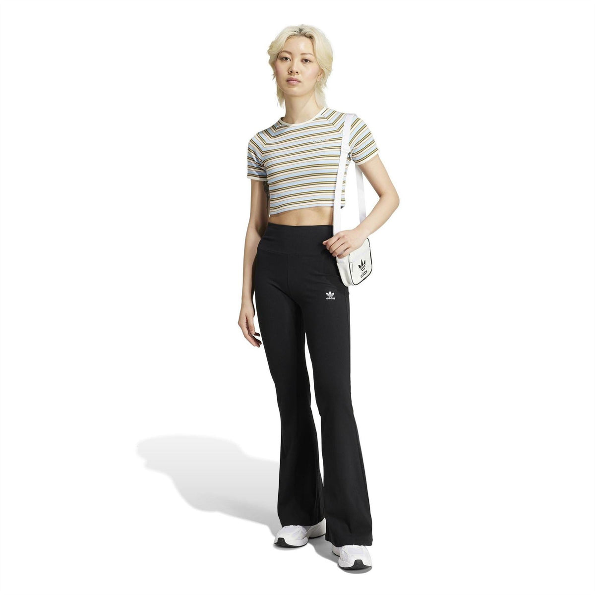 Black flared leggings worn with striped crop top and shoulder bag