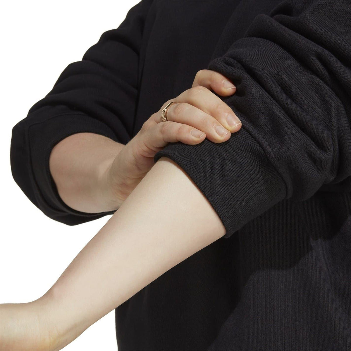 Black cropped sweatshirt sleeve close-up with ribbed cuff and hand