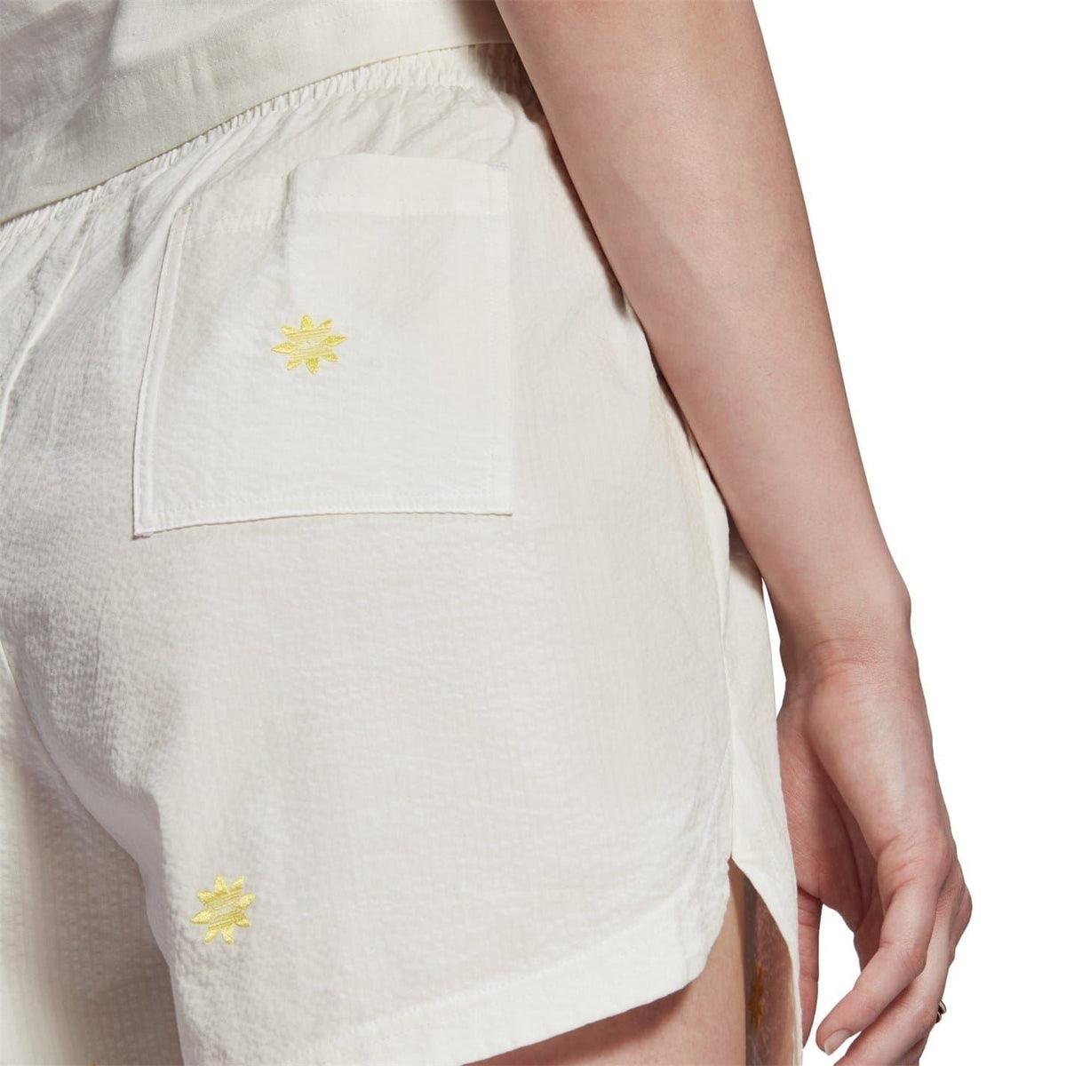 Cream sweat shorts close-up showing back pocket and yellow star emblem