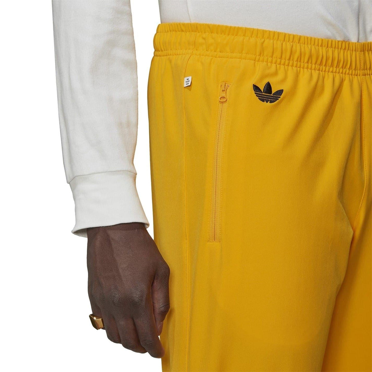 Gold track joggers with zip pocket and adidas trefoil logo on waistband