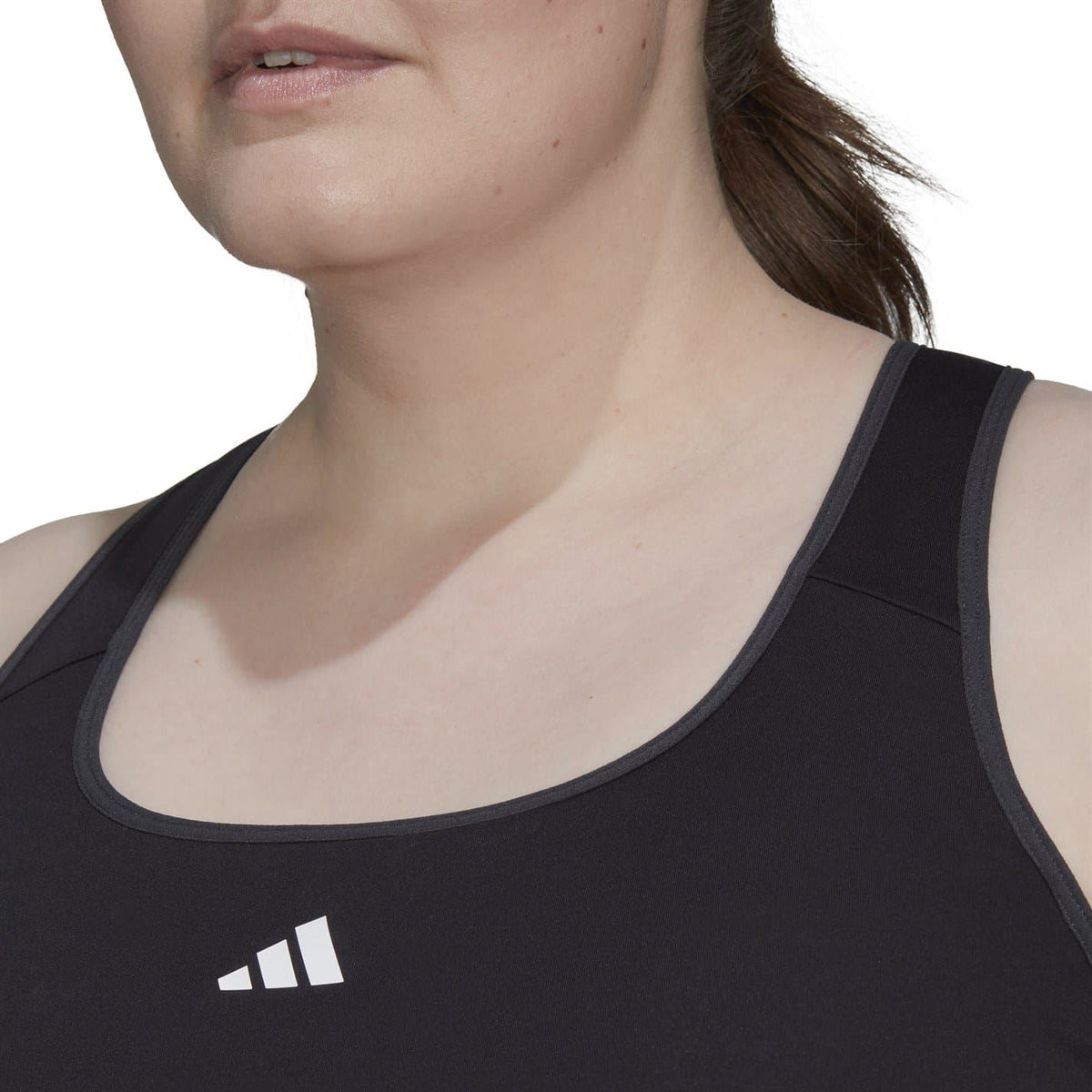 Close-up of black scoop-neck sleeveless bra top with Adidas logo on chest
