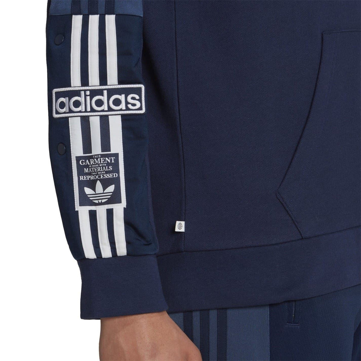 Navy hoodie sleeve with adidas logo patch, striped cuff detail, and kangaroo pocket hem.