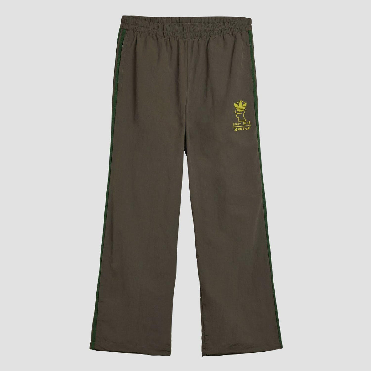 Chocolate track pants with elastic waist, green side stripes, small yellow logo patch