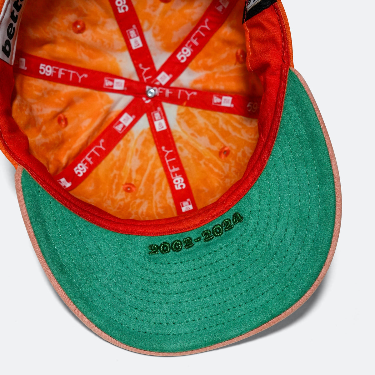 Orange cap interior with '59FIFTY' tags and green underside brim stitching