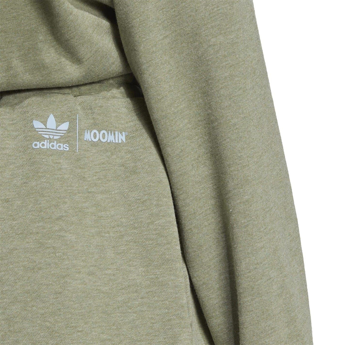 Close-up of green sweat shorts showing adidas and Moomin logo print