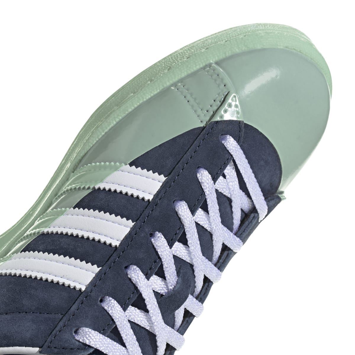 Side view of navy-and-mint trainers with white striped details and light-blue laces