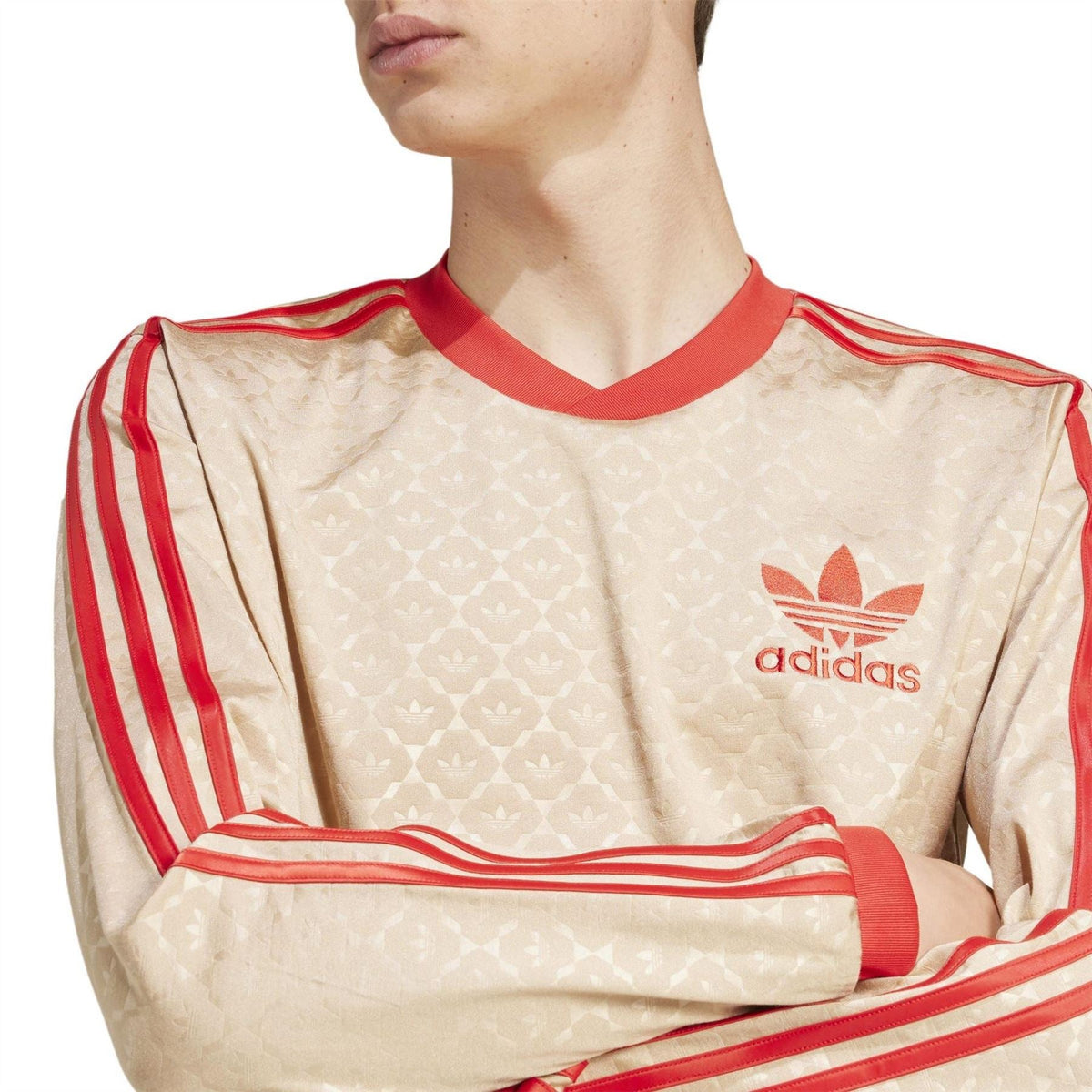 Beige t-shirt close-up with red adidas logo and textured pattern