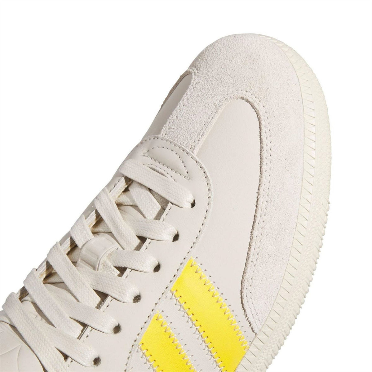 Close-up of off-white suede sneaker upper with yellow stripe detail and white lace-up