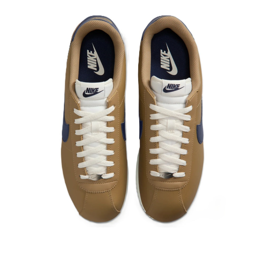 Low-top sneakers with tan uppers, cream laces, navy heel lining, and NIKE logo on tongue