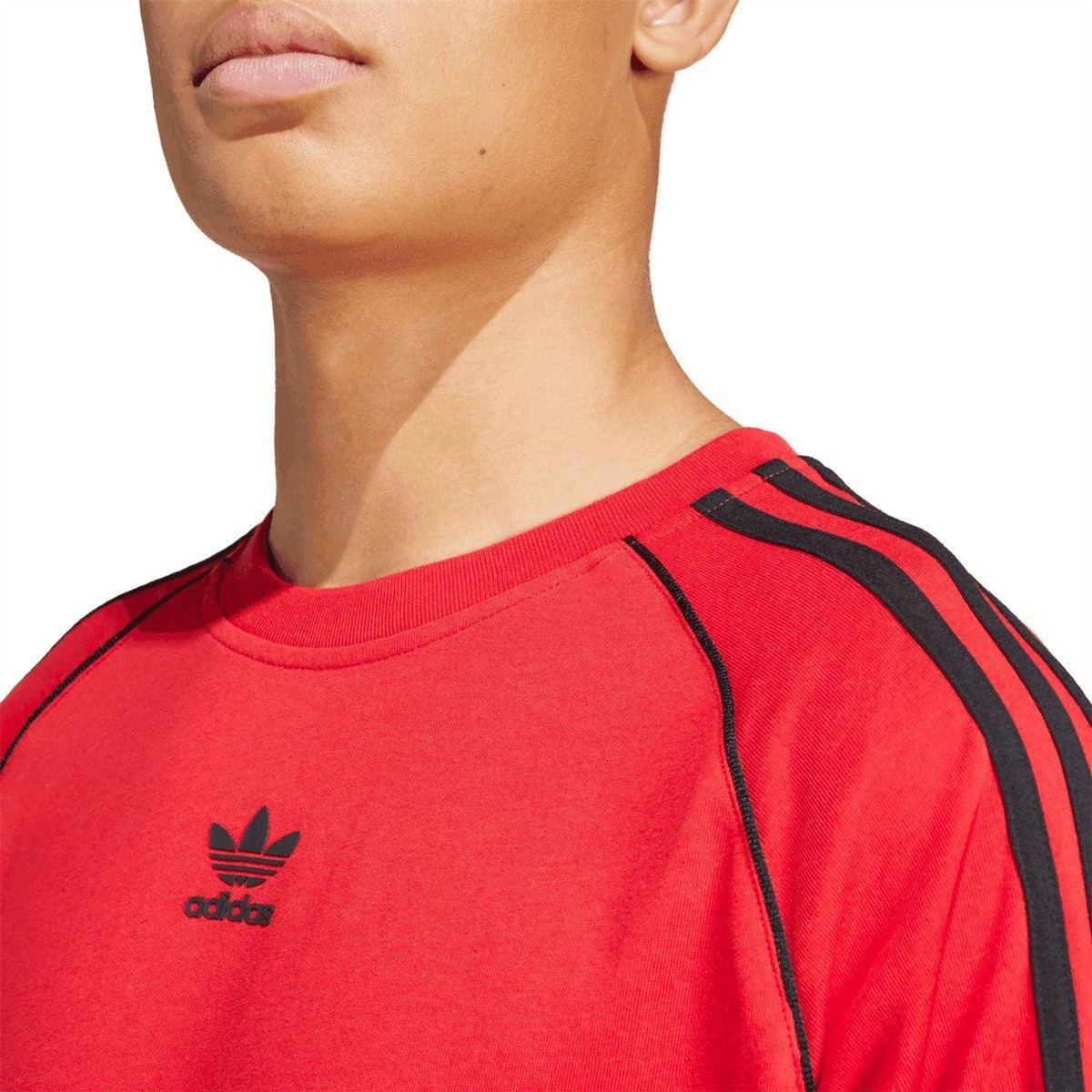 Close-up of red adidas T-shirt neckline with trefoil logo and black shoulder stripes