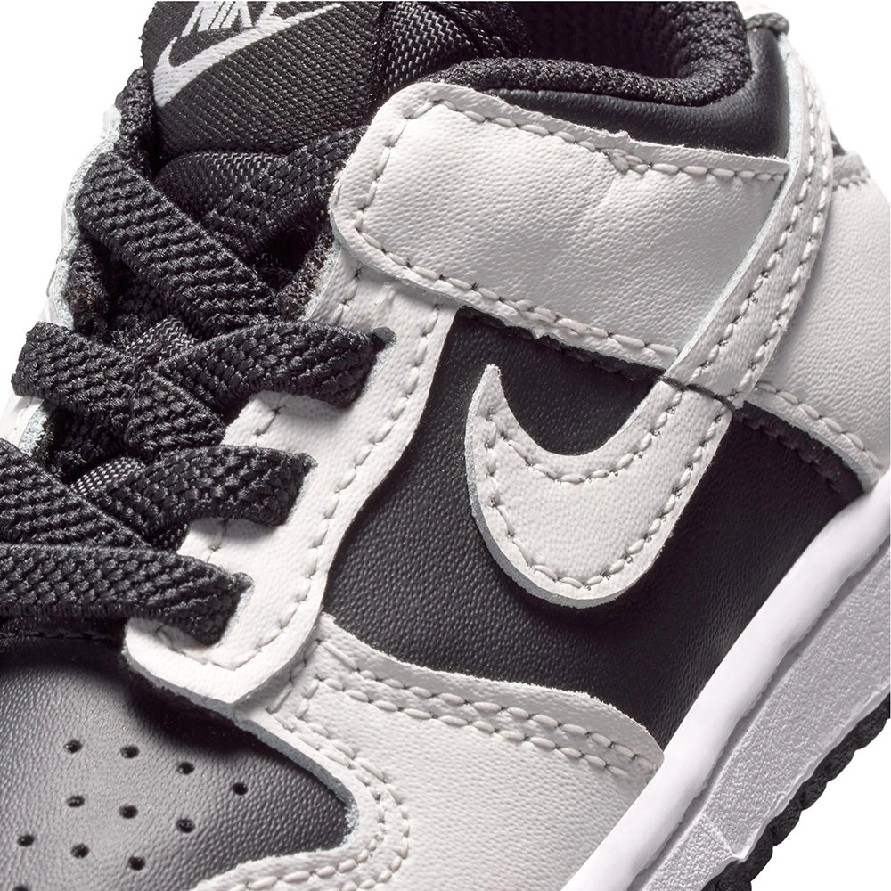 Toddler Nike Dunk Low close-up, white swoosh on black panel with woven laces