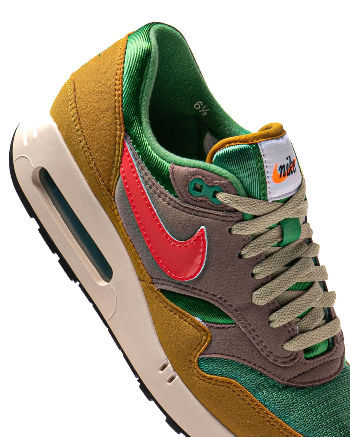 Air Max 1 PRM sneaker close-up, green laces, red swoosh, brown suede and air window