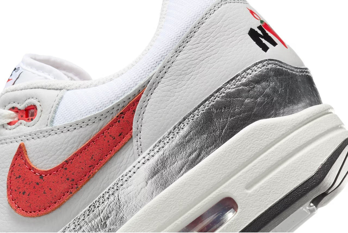 Nike Air Max 1 PRM sneaker close-up, white leather with red swoosh and silver panel