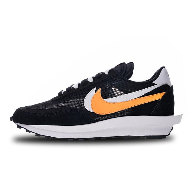 Black running shoes with white midsole and bright orange swoosh and panel accents