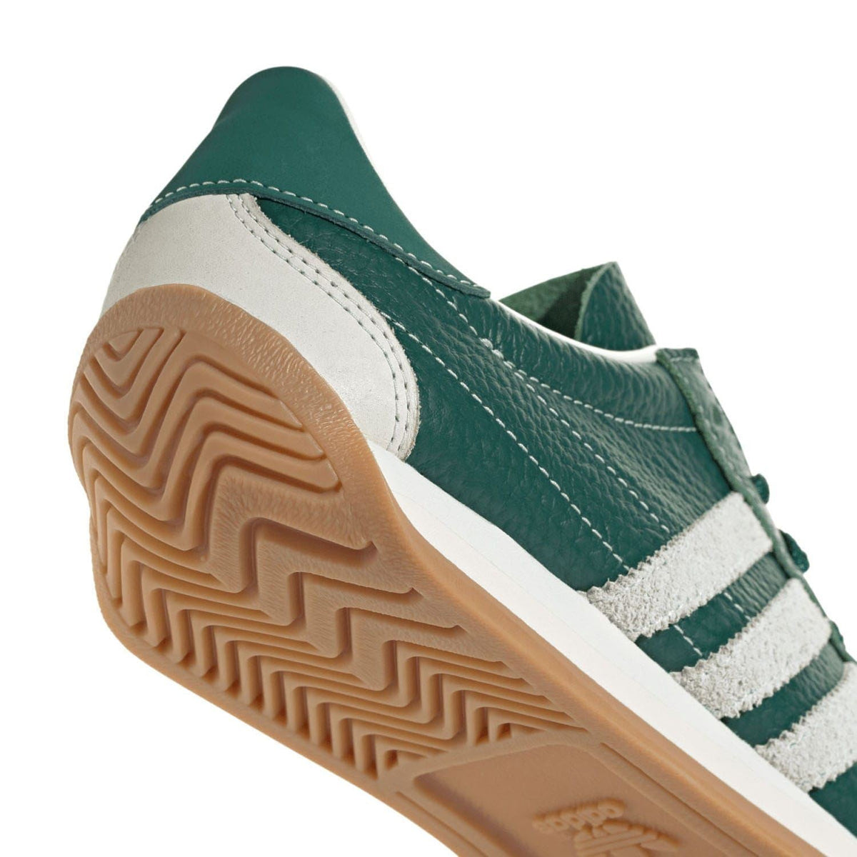 Side view of green and white adidas Originals trainers with treaded gum sole