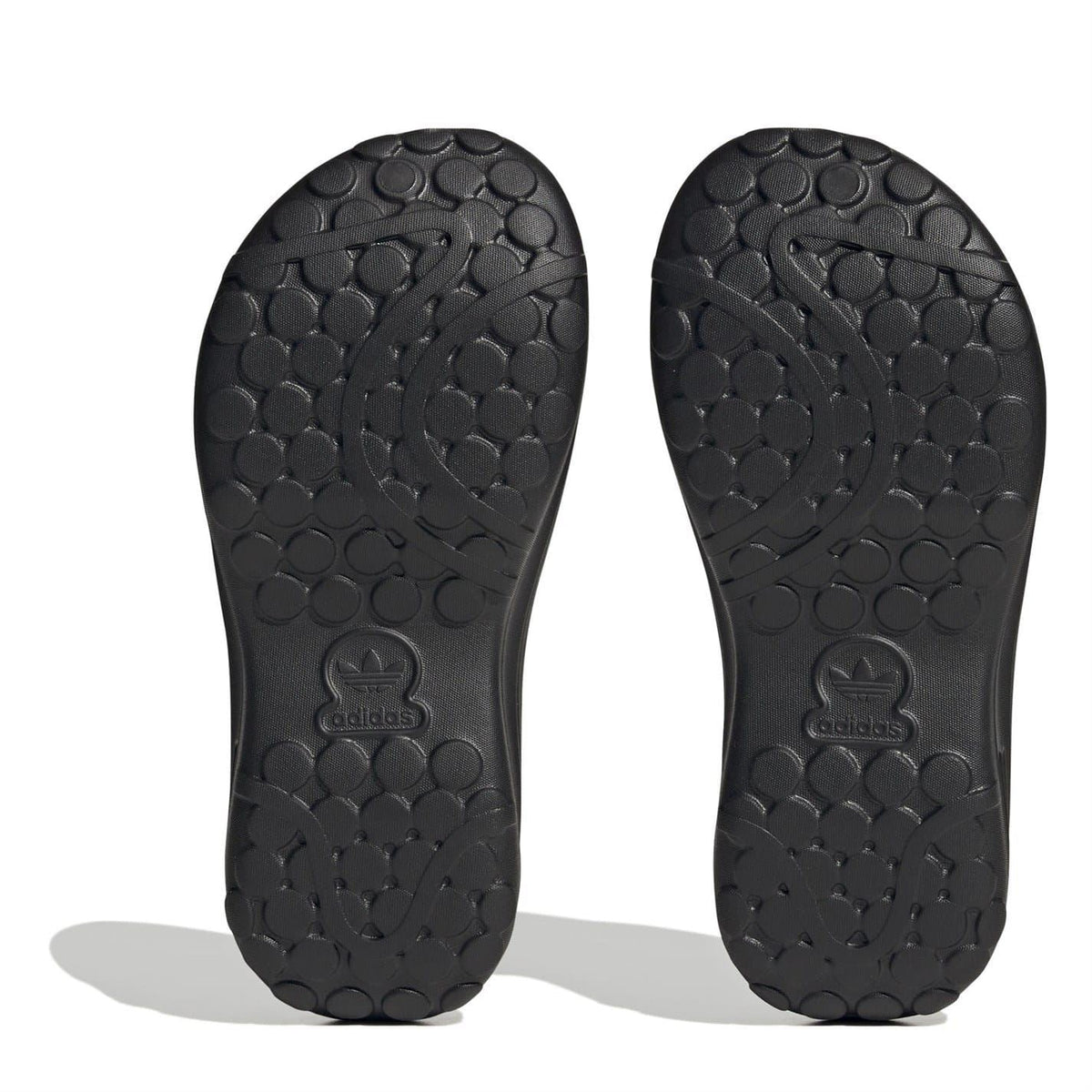Black low-top trainers outsole view with circular tread pattern and embossed adidas logo