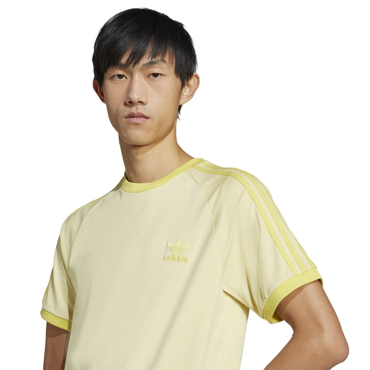 Light yellow raglan T-shirt close-up: adidas Originals trefoil logo and ribbed neckline
