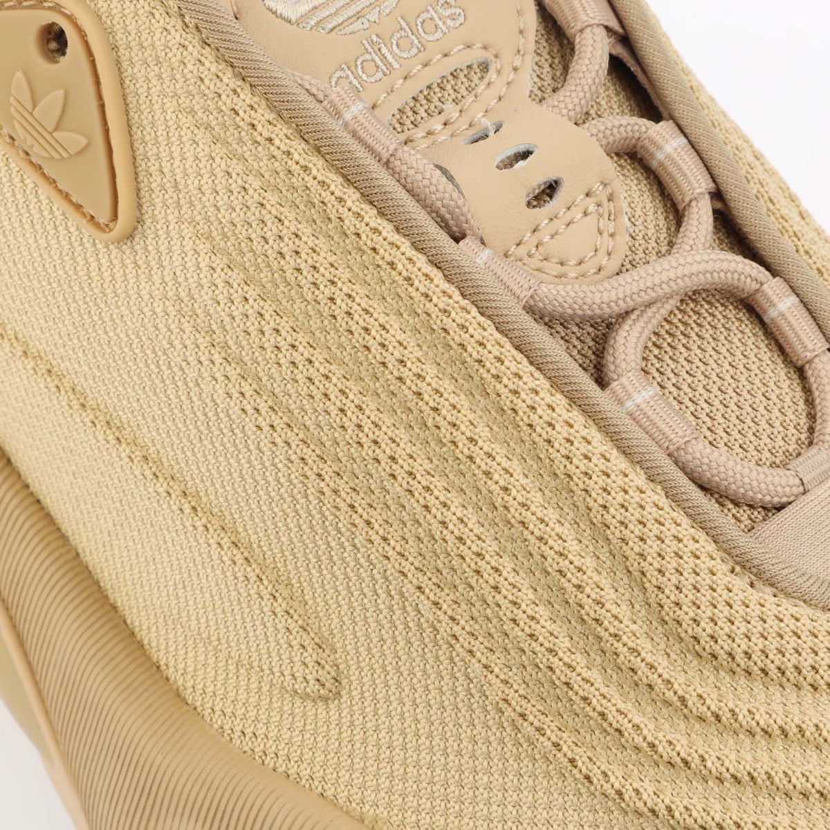 Beige knitted upper with adidas trefoil logo, seam lines, and lace eyelets
