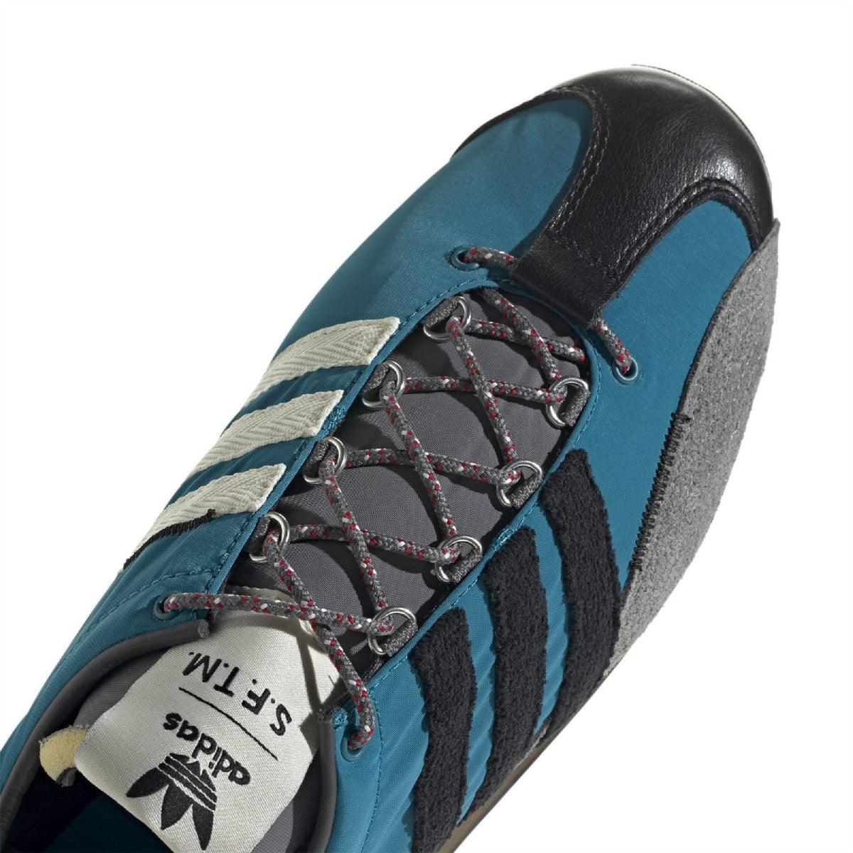 Teal leather-look sneaker close-up: lace-up with dark eyelets and three stripes