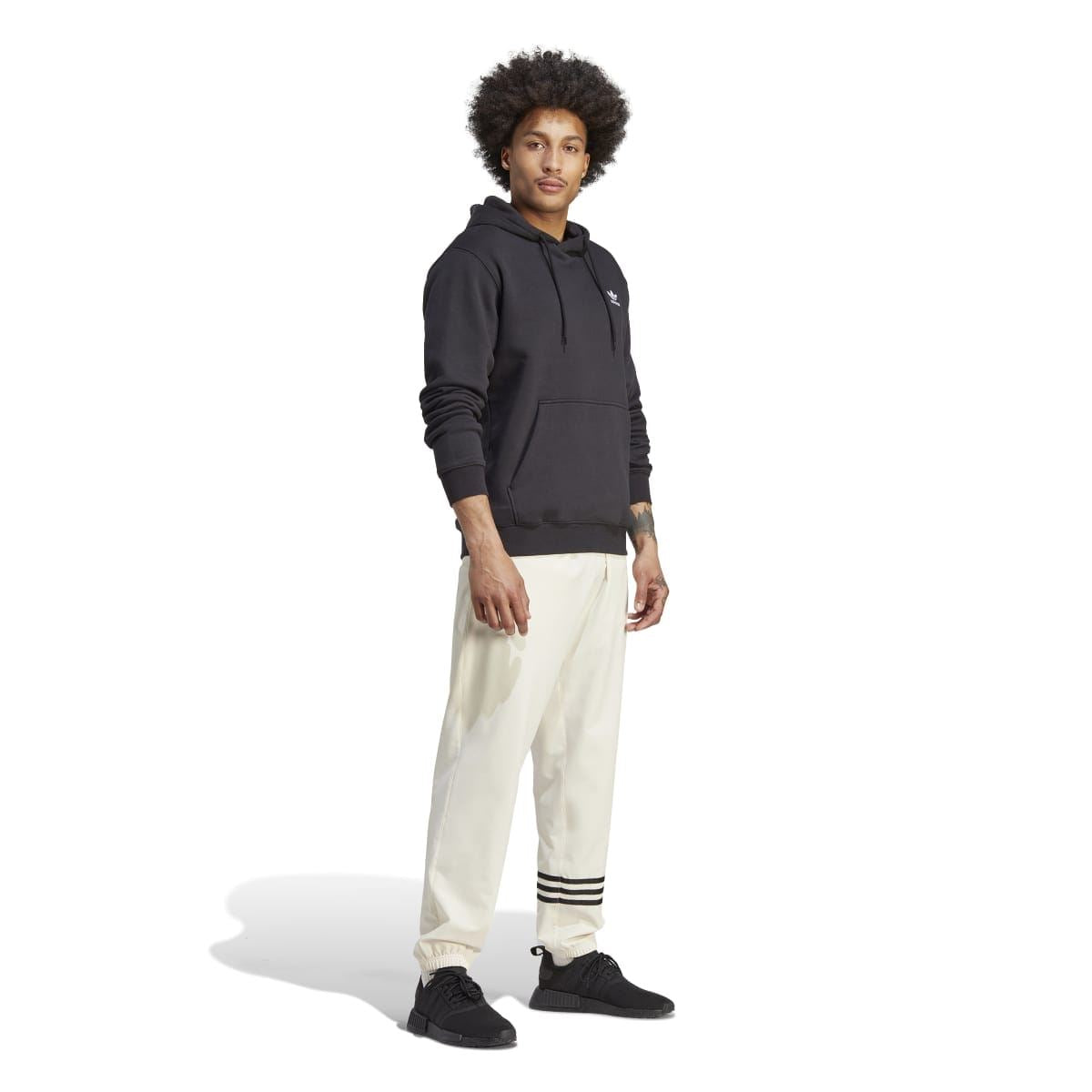 Black adidas Trefoil hoodie with drawstring hood, worn with light pants