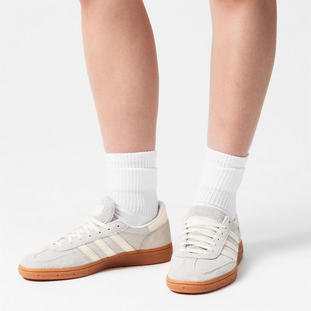White and tan low-top sneakers on legs with white crew socks