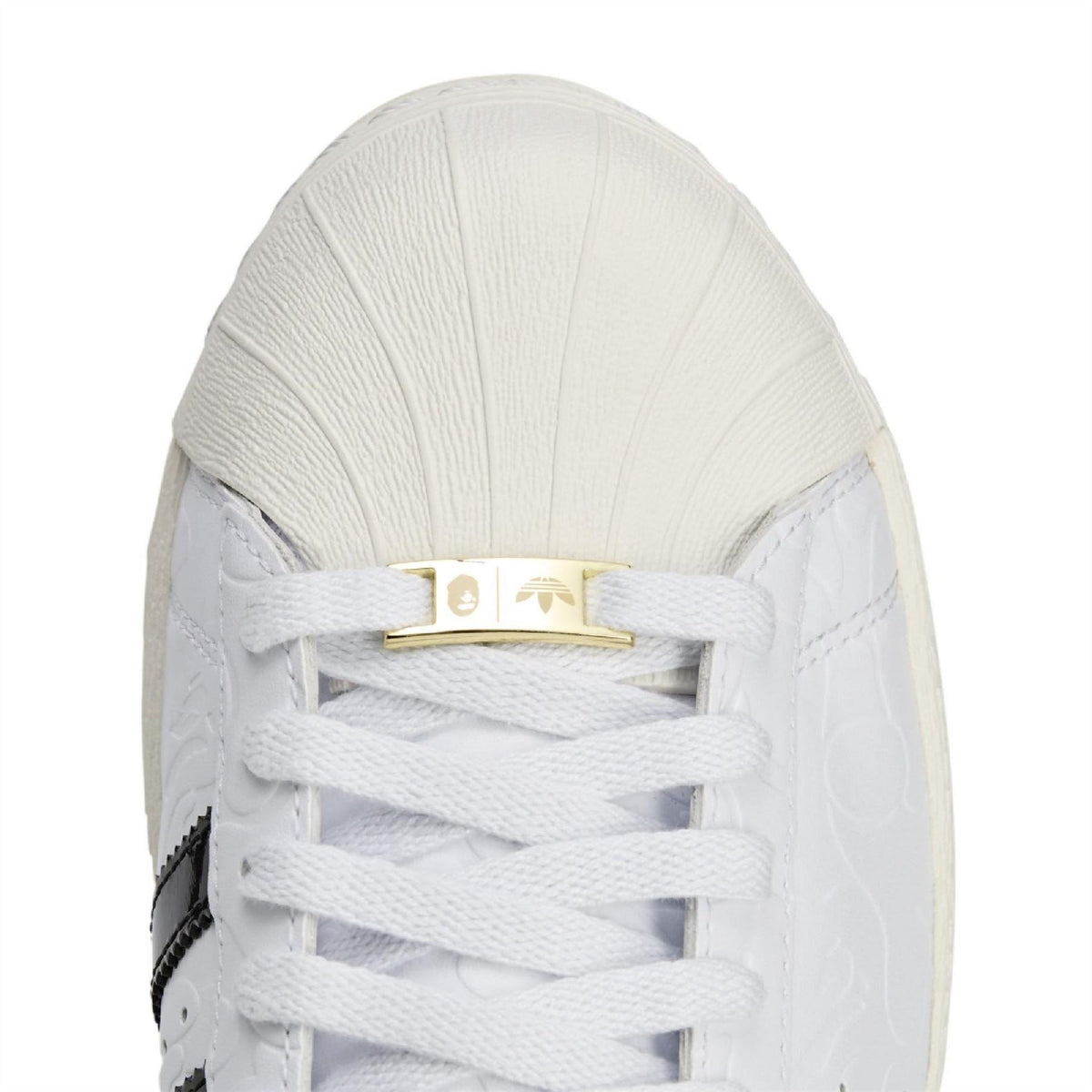 White Adidas Originals SSTR sneaker close-up of lace-up tongue with gold tag