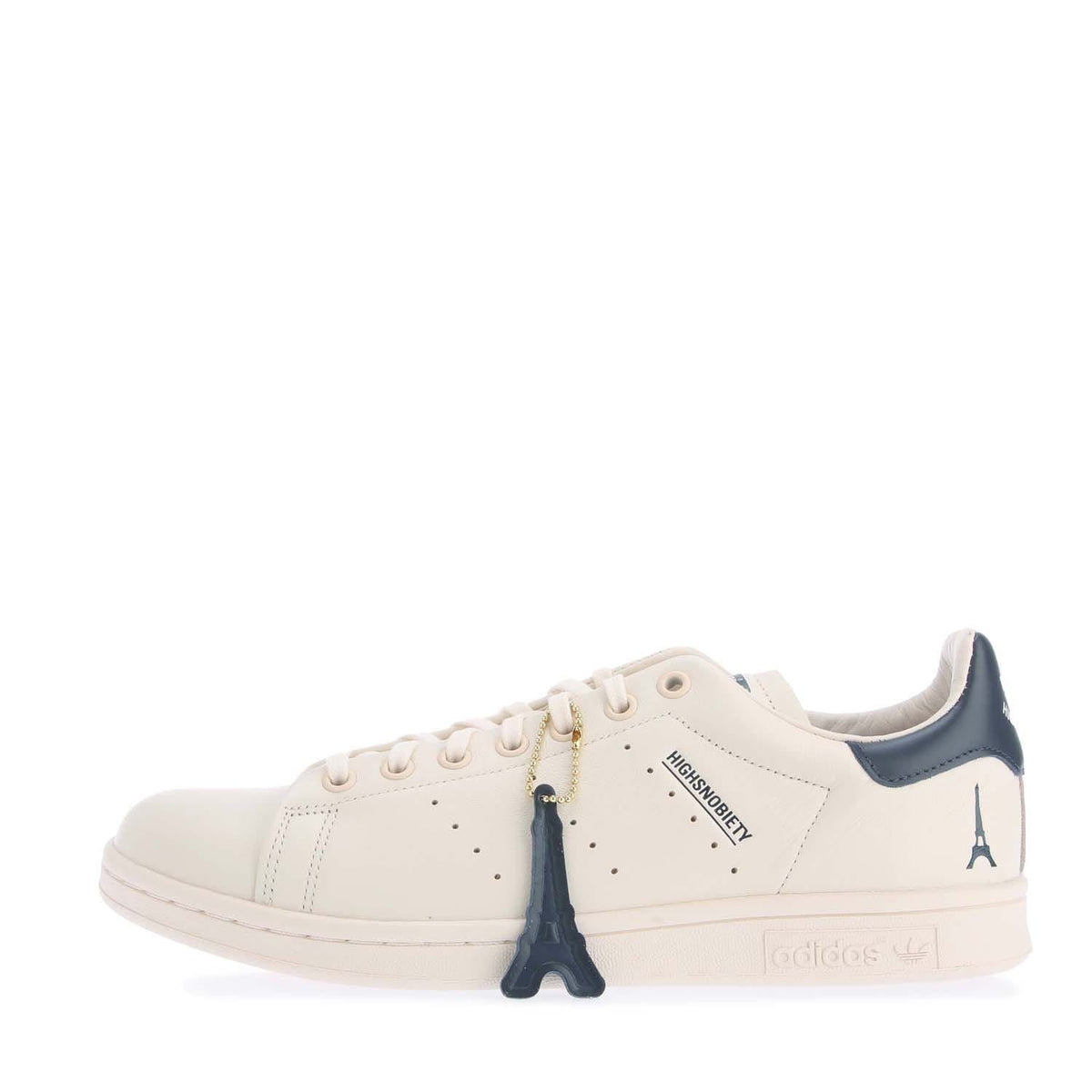 White high-top sneakers with navy accents, lace-up front and hanging charm detail.