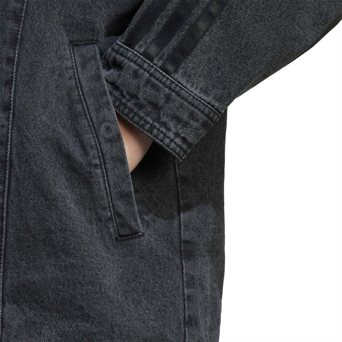 Black denim jacket sleeve detail with button cuff and vertical seam stitching