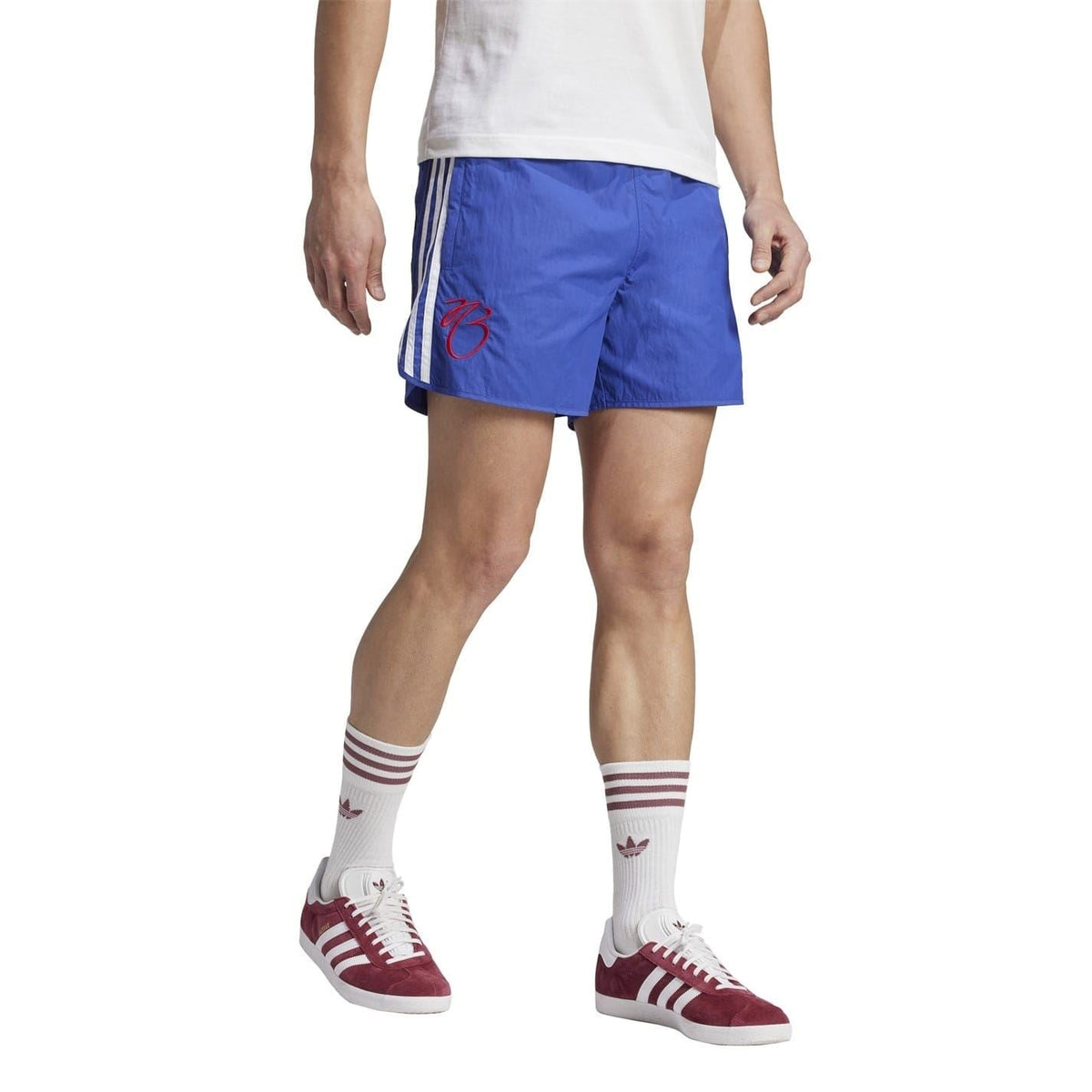 Blue soccer shorts on model, elastic waist, white side stripes, red "73" graphic