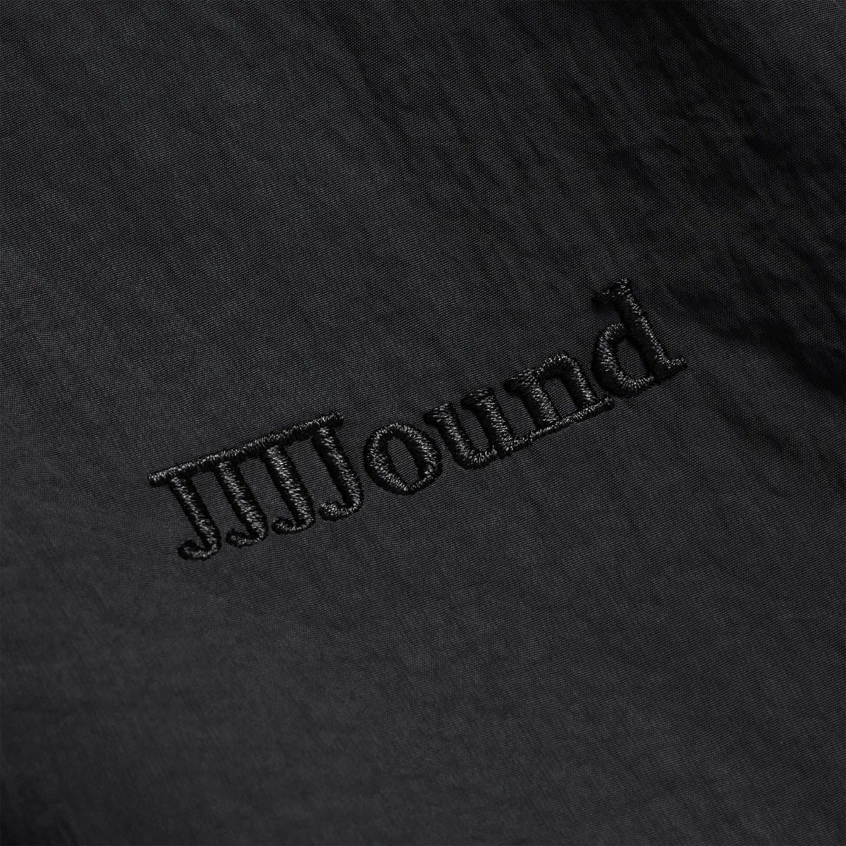 Black embroidered JJJJound lettering on track jacket