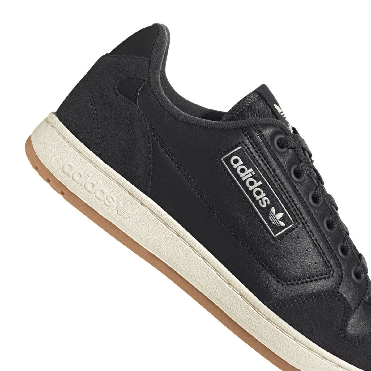 Black adidas trainer close-up with side label and cream outsole edge