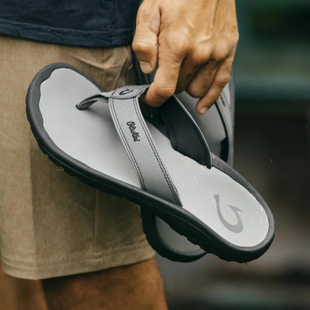 Gray-and-white flip-flop sandals held by hand, showing strap label and molded sole