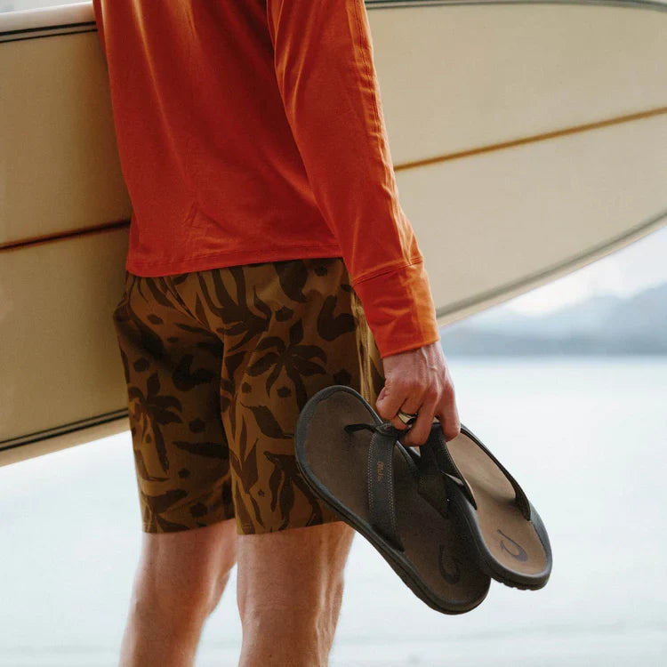 Brown flip-flops held in hand with textured strap and sole
