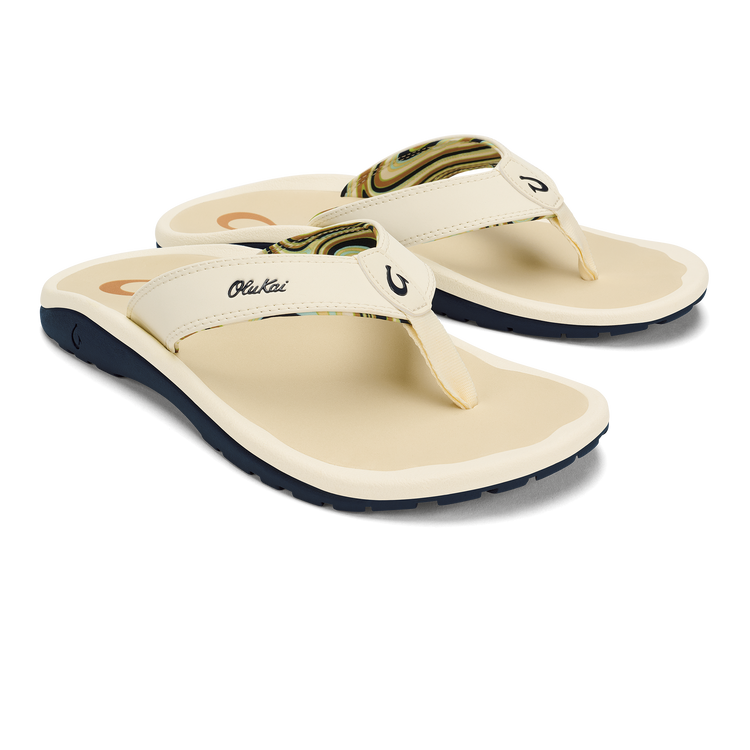Cream flip-flop sandals with green patterned straps and OluKai logo