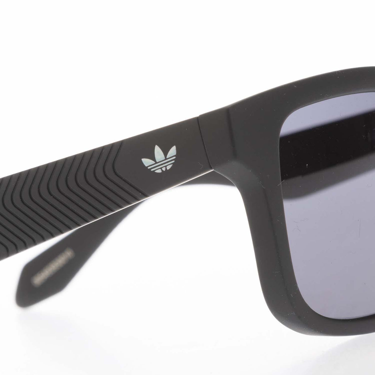 Black temple close-up with adidas trefoil logo and textured grip pattern