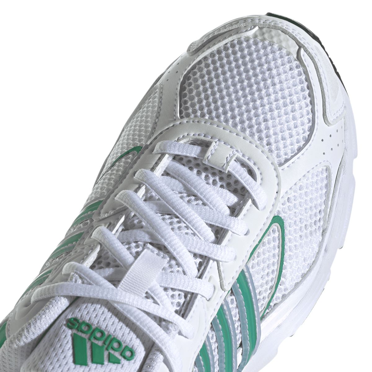 Close-up of white trainer upper with green side stripe, lace eyelets, and mesh texture