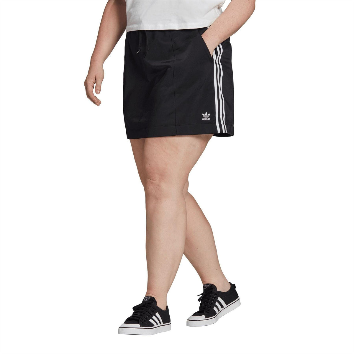 Black midi skirt with white side stripes and Adidas logo, worn with sneakers