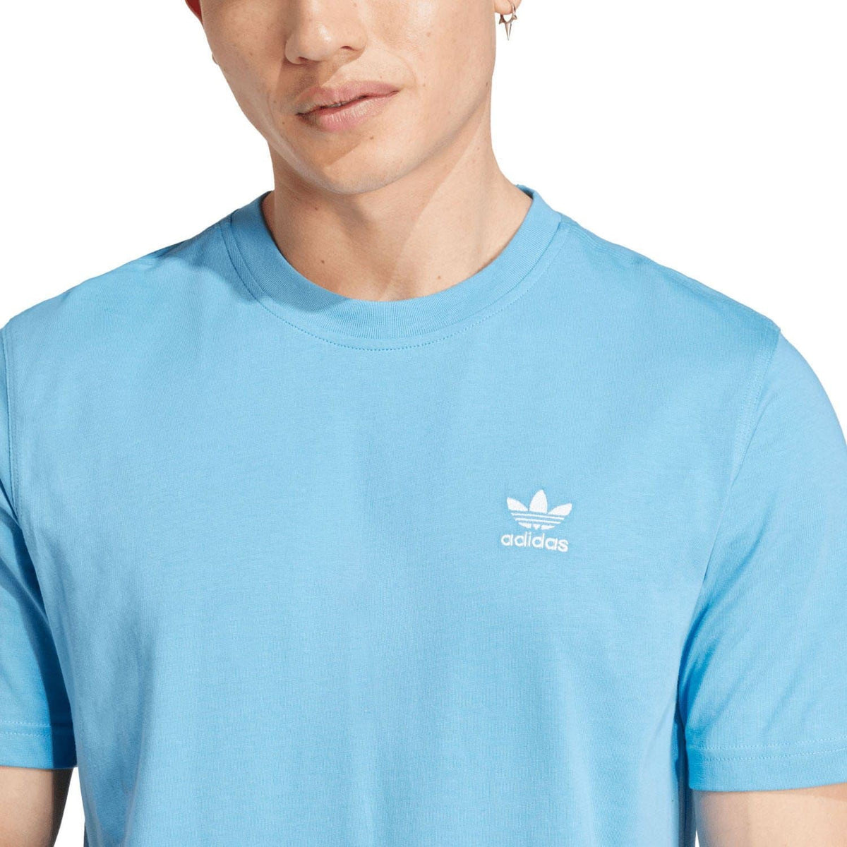 Blue T-shirt close-up showing adidas trefoil logo on chest and crew neck