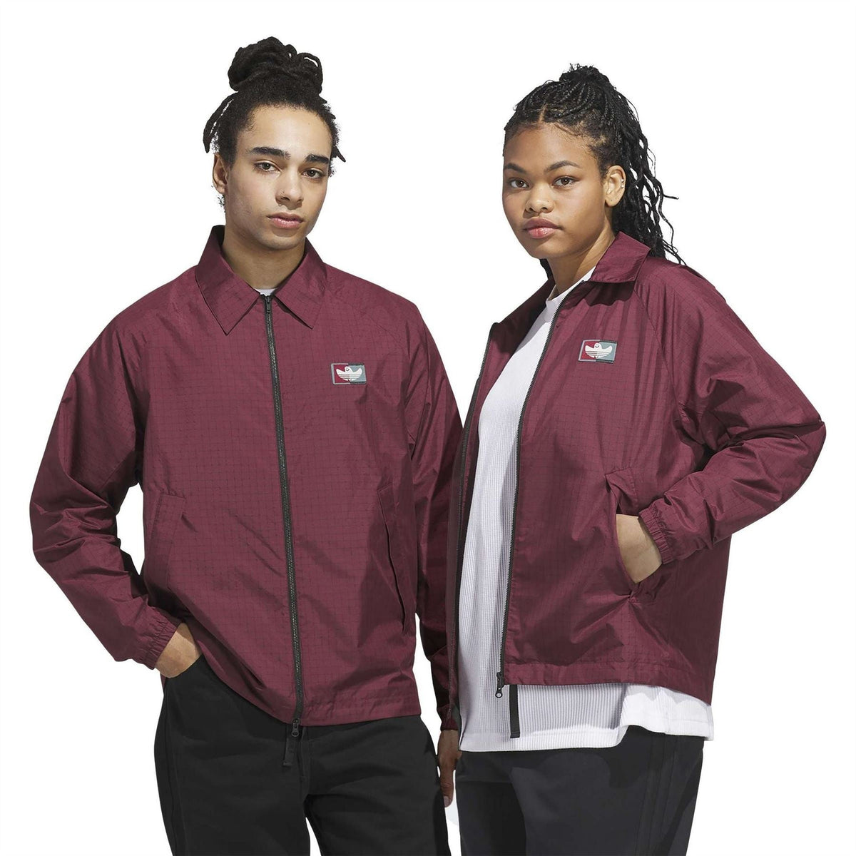 Burgundy coach jacket on model, zip front, stand collar, chest logo patch, long sleeves