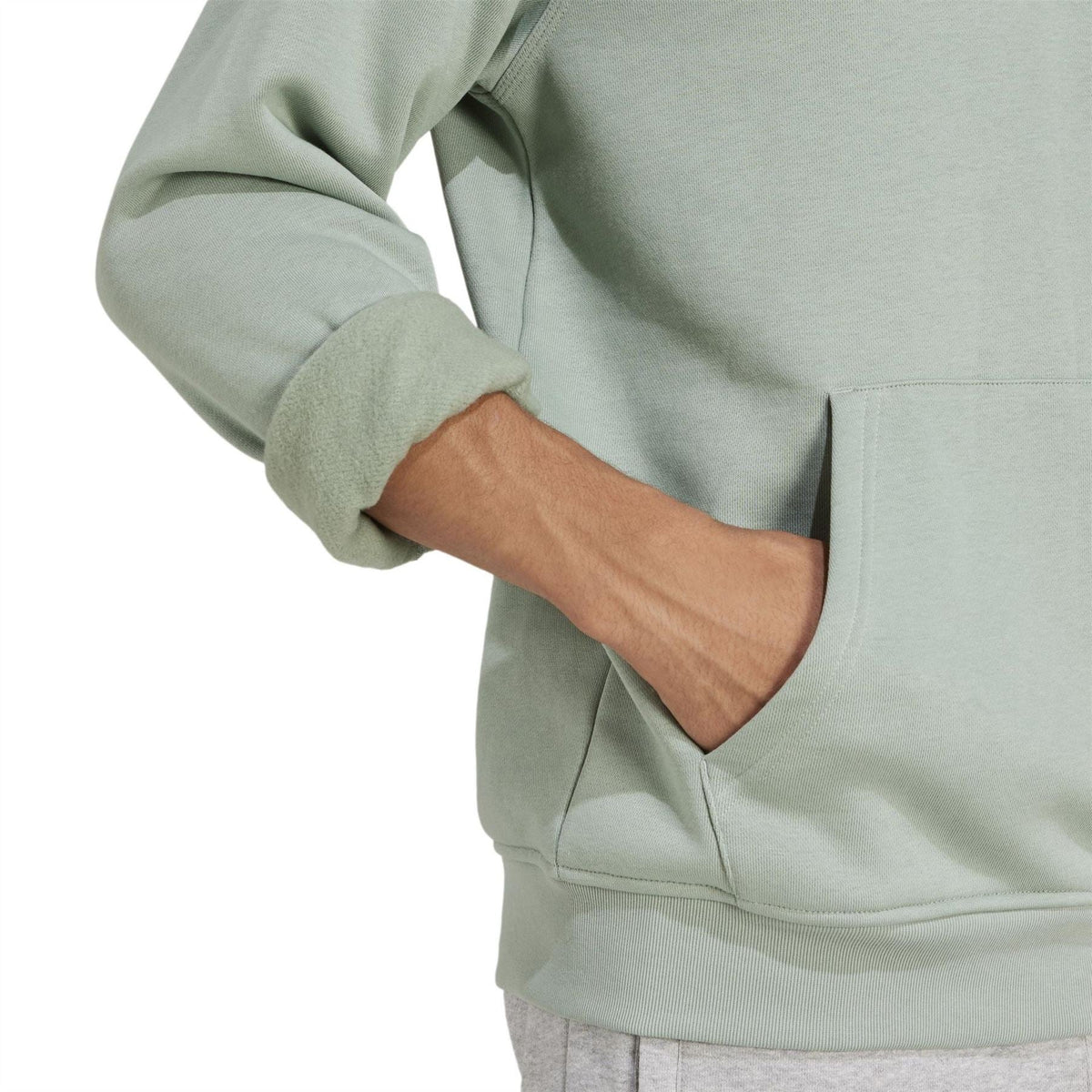 Light sage green hooded sweatshirt close-up, ribbed cuff and kangaroo pocket
