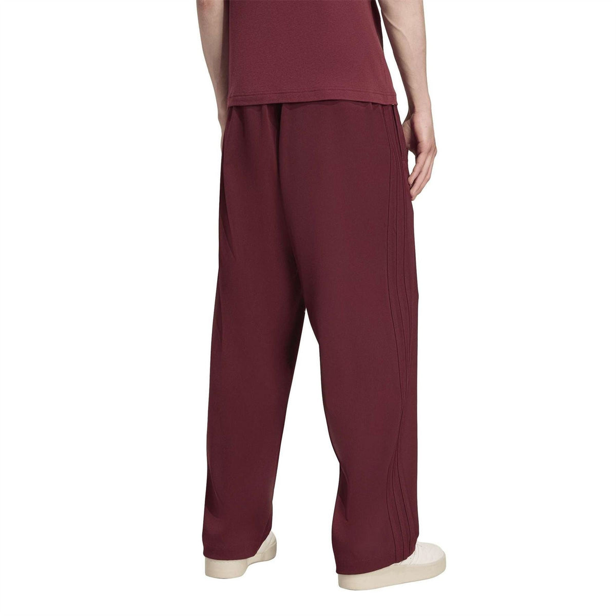 Maroon track pants with draped fabric, elastic waistband, and straight baggy legs