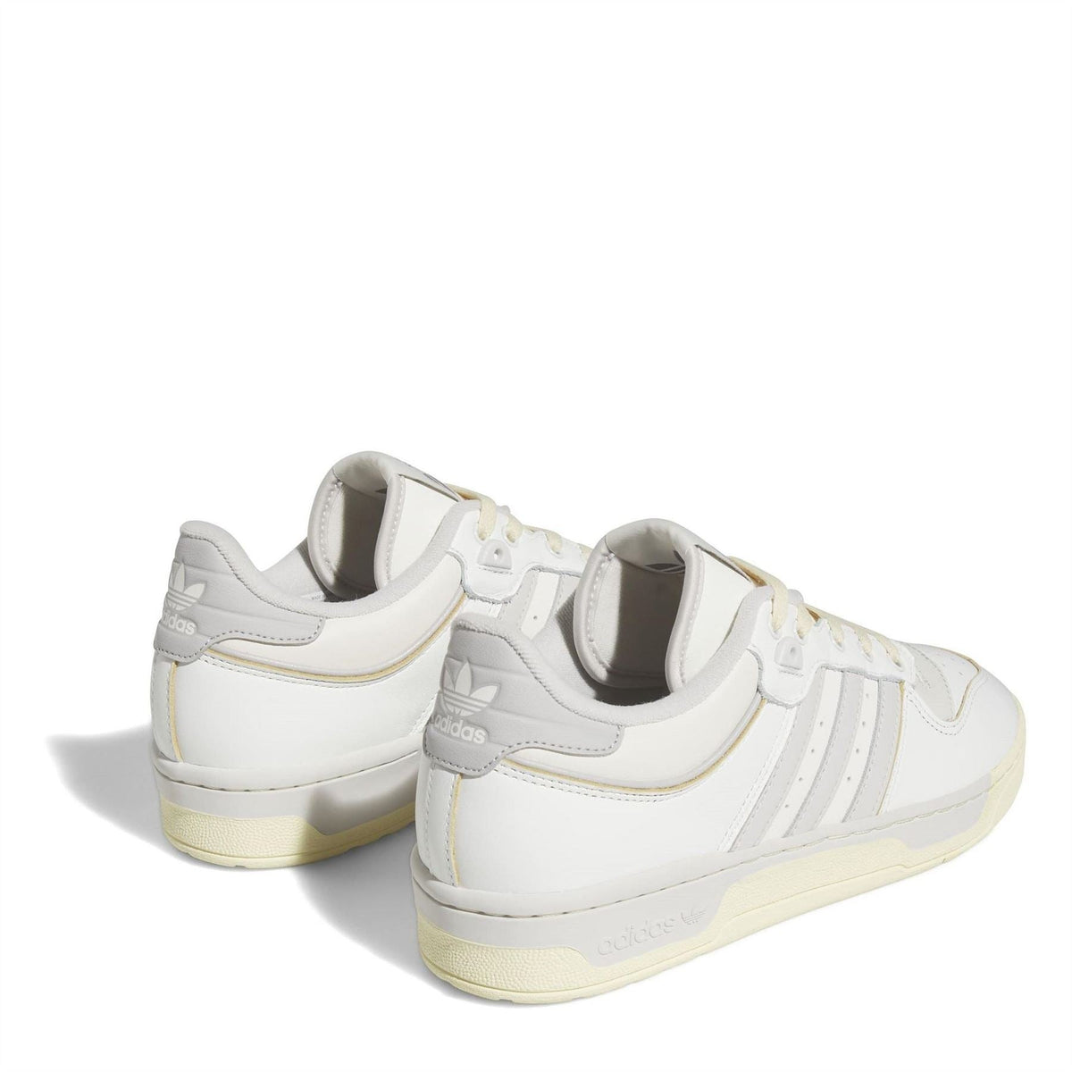 White adidas low-top trainers from heel view with three stripes and gum outsole.