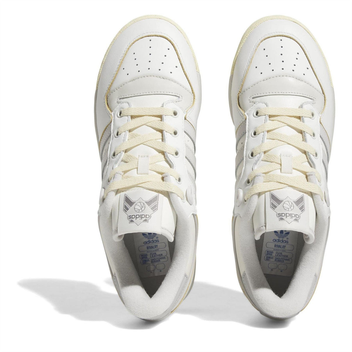 White lace-up trainers with perforated toe box and visible tongue label inside.