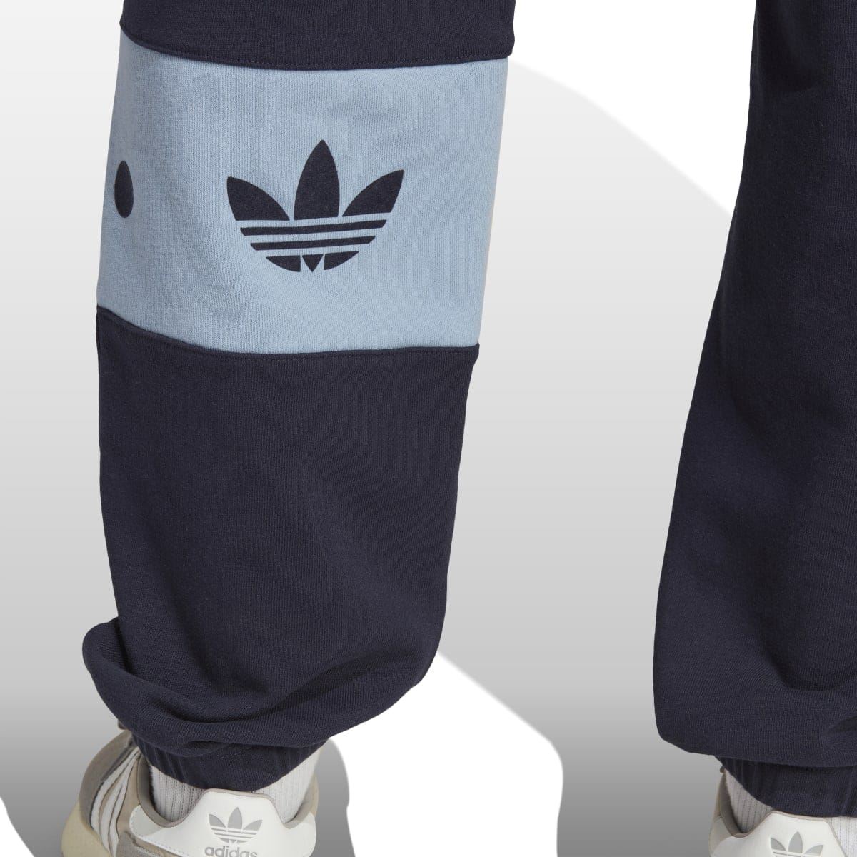Navy joggers with light-blue lower-leg band and trefoil logo; ribbed cuff at ankle