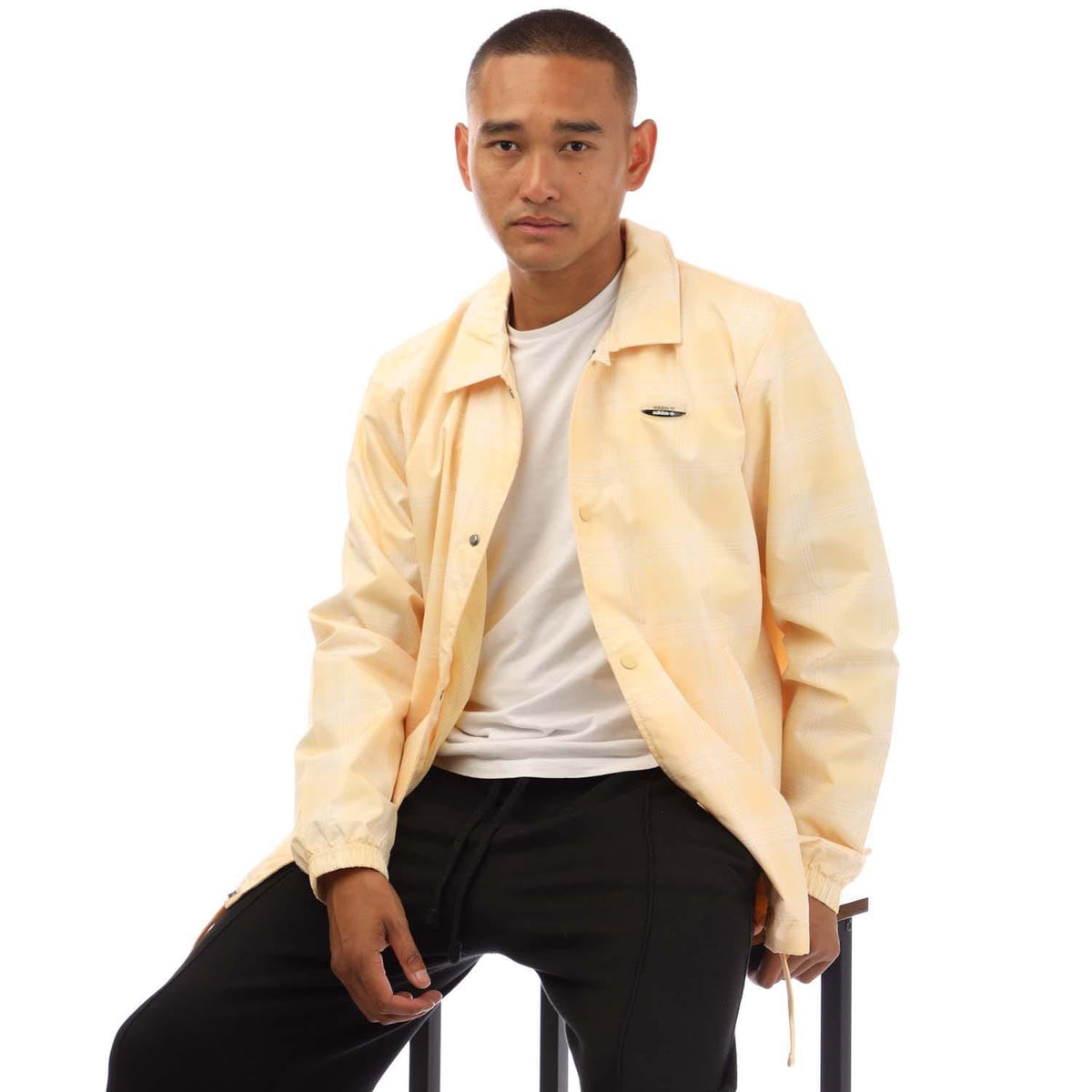 light yellow adidas coach jacket with stand collar, snap placket, and chest logo