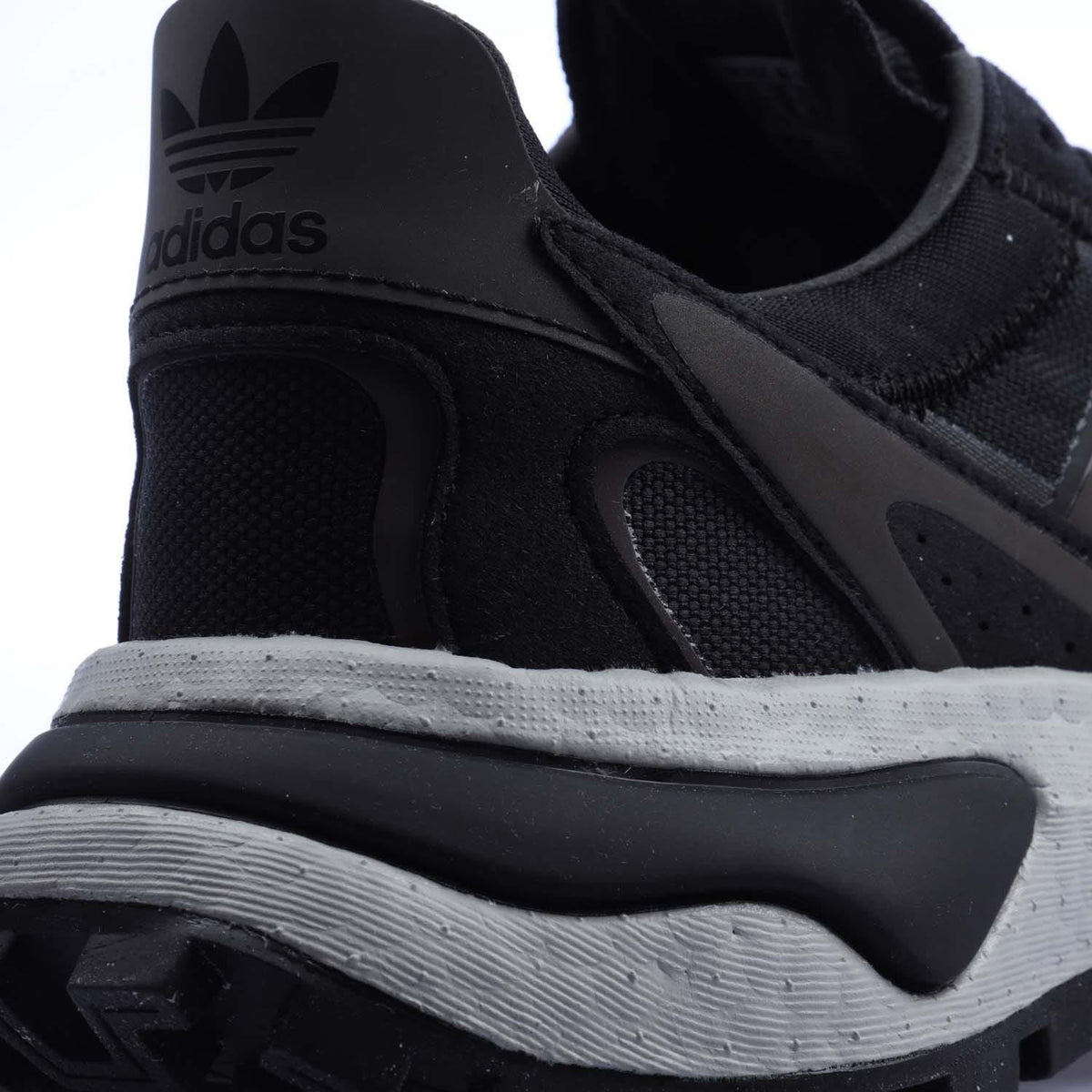 Black heel close-up with adidas trefoil logo and cushioned midsole edge.