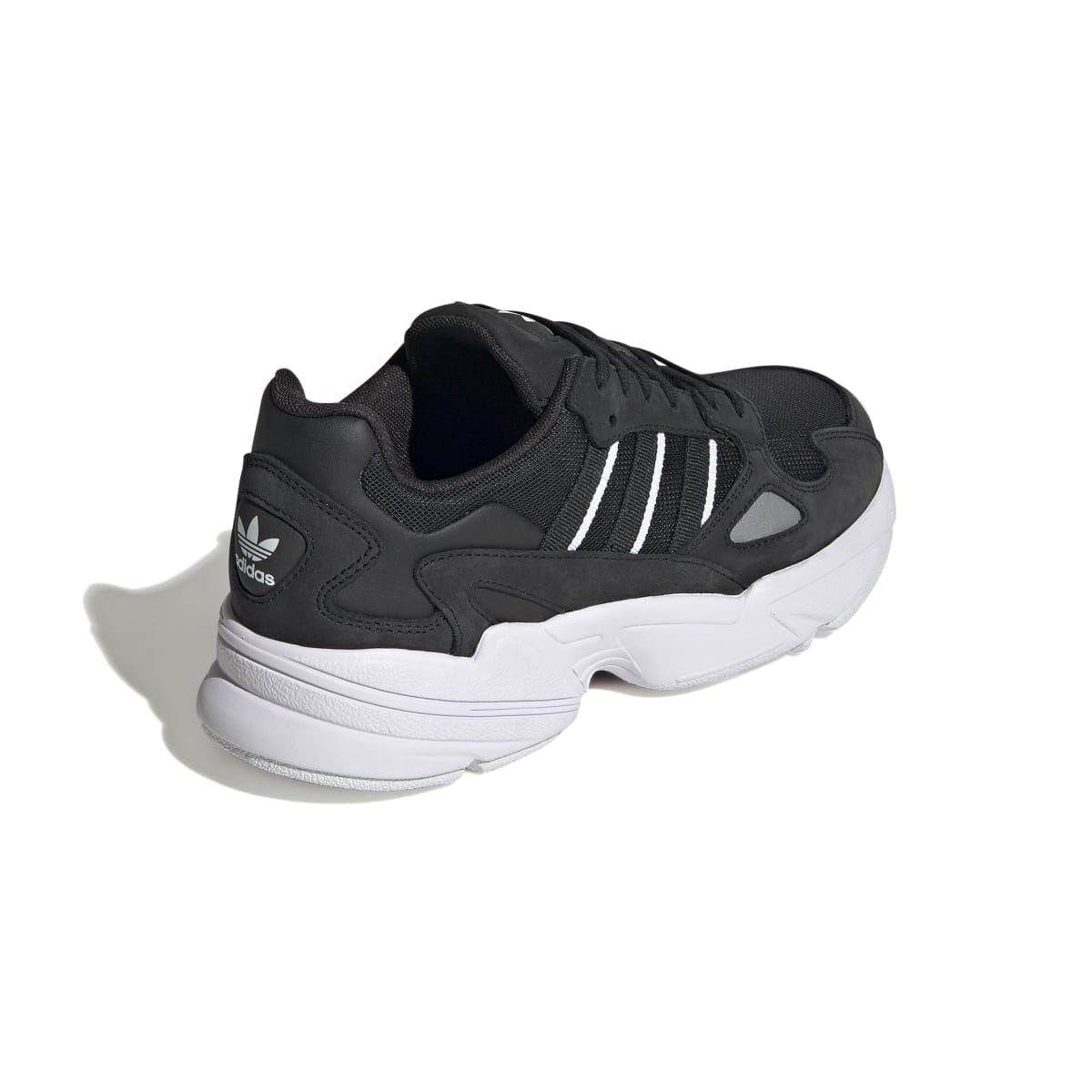 Black low-top sneakers with three stripes and sculpted white midsole, heel side view
